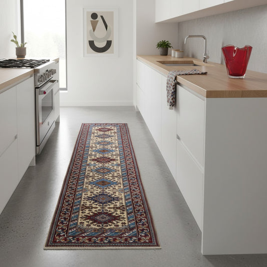 Elegante tappeto Shirvan annodato a mano in pura lana con colori vegetali. Dimensioni 301x83 cm, fondo beige con cornice rossa e motivi geometrici tradizionali afgani. Ideale per corridoi e ambienti raffinati.