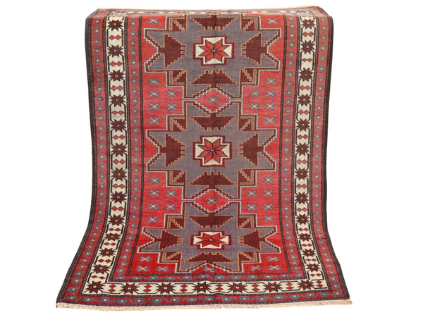 Tappeto Kazak 181x113 cm con motivo geometrico a stelle in rosso, blu e beige, annodato a mano con lana pregiata e ordito in cotone robusto.