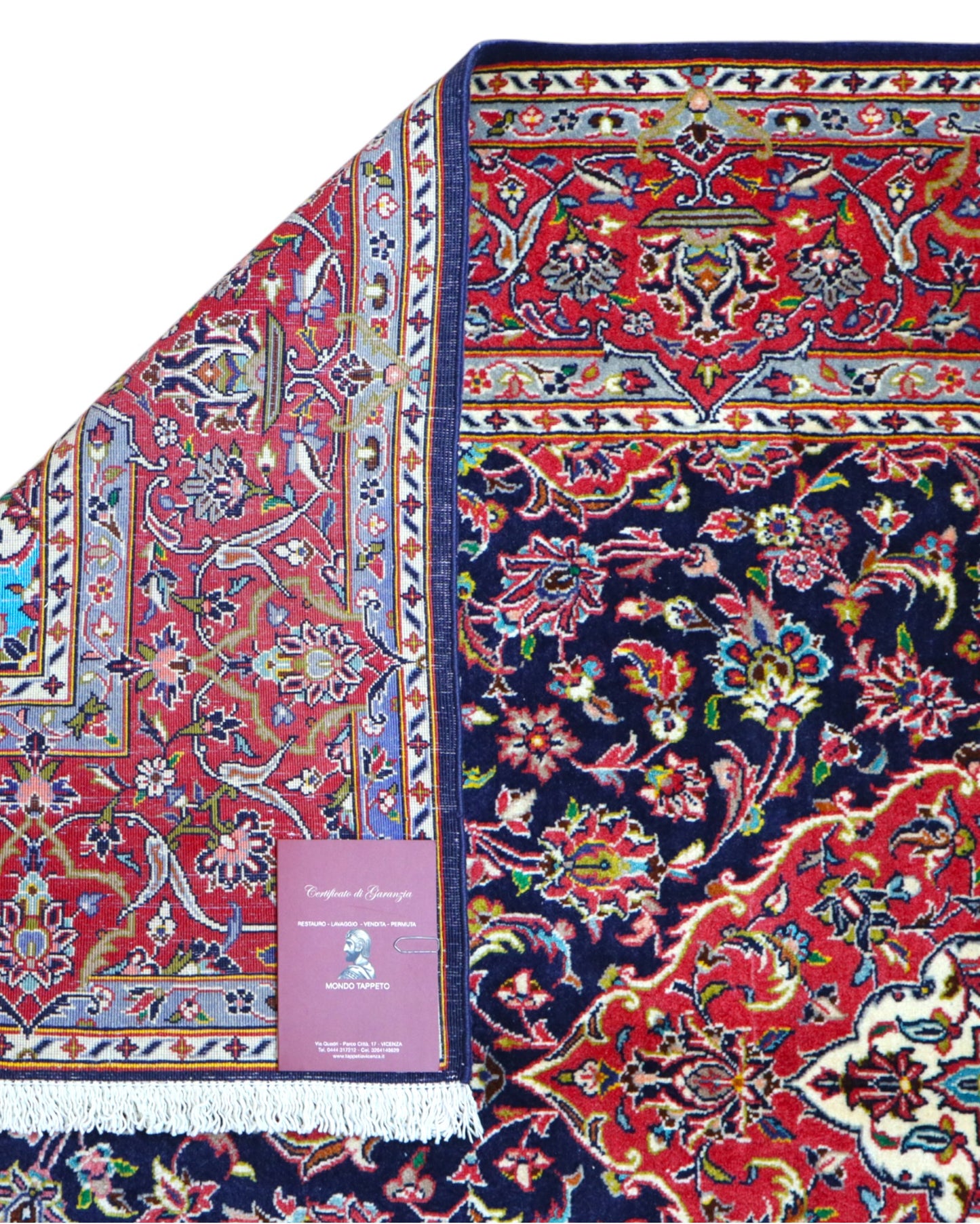 Tappeto Kashan persiano 225x142 cm, annodato a mano, fondo blu notte con motivo floreale e cornice rossa decorata, lana mista seta, certificato di autenticità incluso.