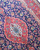 Tappeto Kashan persiano 225x142 cm, annodato a mano, fondo blu notte con motivo floreale e cornice rossa decorata, lana mista seta, certificato di autenticità incluso.