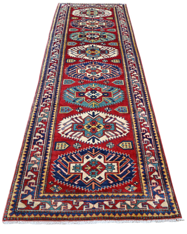 Passatoia Kazak afgana 351x91 cm annodata a mano in lana, con un design audace caratterizzato da motivi geometrici su un fondo rosso intenso.
