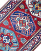 Passatoia Kazak afgana 351x91 cm annodata a mano in lana, con un design audace caratterizzato da motivi geometrici su un fondo rosso intenso.