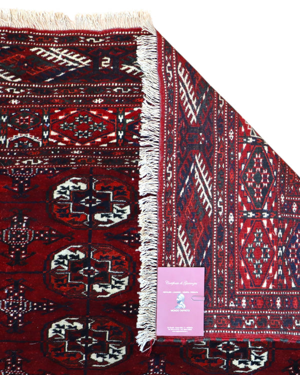 Tappeto Bukhara 324x205 cm con fondo rosso scuro e motivi a gul geometrici in nero, avorio e blu, tramato ed annodato a mano, provenienza Bukhara.