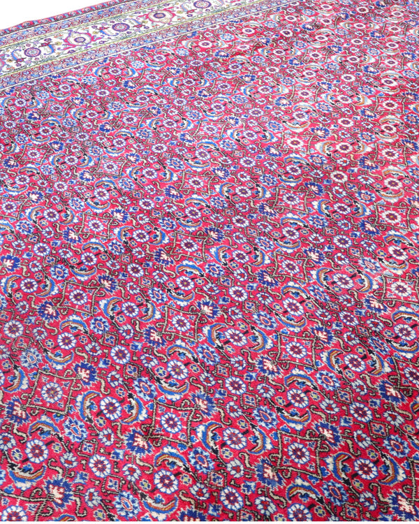 Tappeto Ushak 424x320 cm, fondo rosso con motivi ripetuti geometrici e floreali, cornice giallo-avorio, annodato a mano in lana vegetale, Turchia.