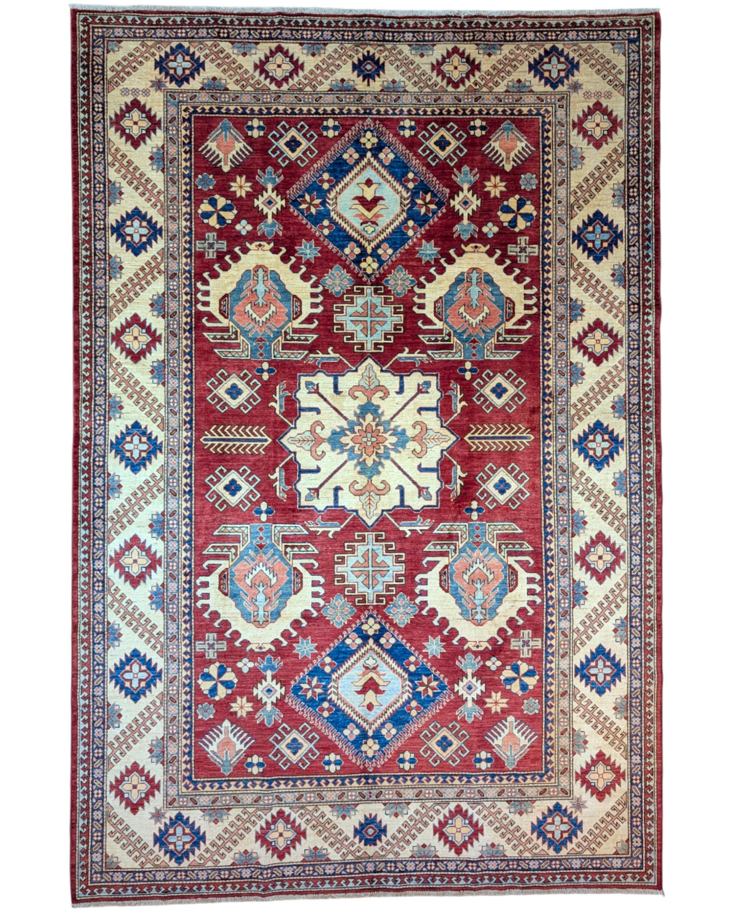 Tappeto Kazak 330x224 cm con fondo rosso, medaglione centrale avorio e motivi geometrici blu e azzurri, tramato ed annodato a mano, provenienza Caucaso.
