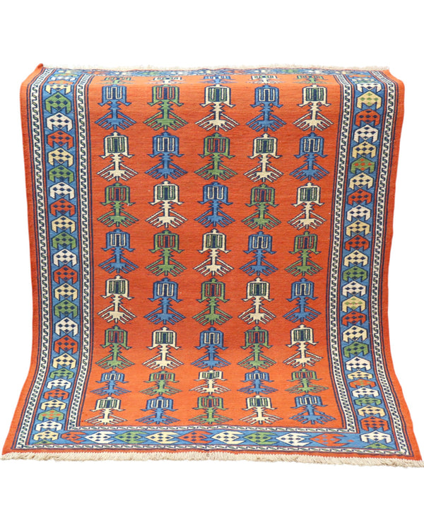 Tappeto Kilim 181x130 cm con motivi geometrici e figure stilizzate in blu, verde e rosso su fondo arancione e bordura decorata.