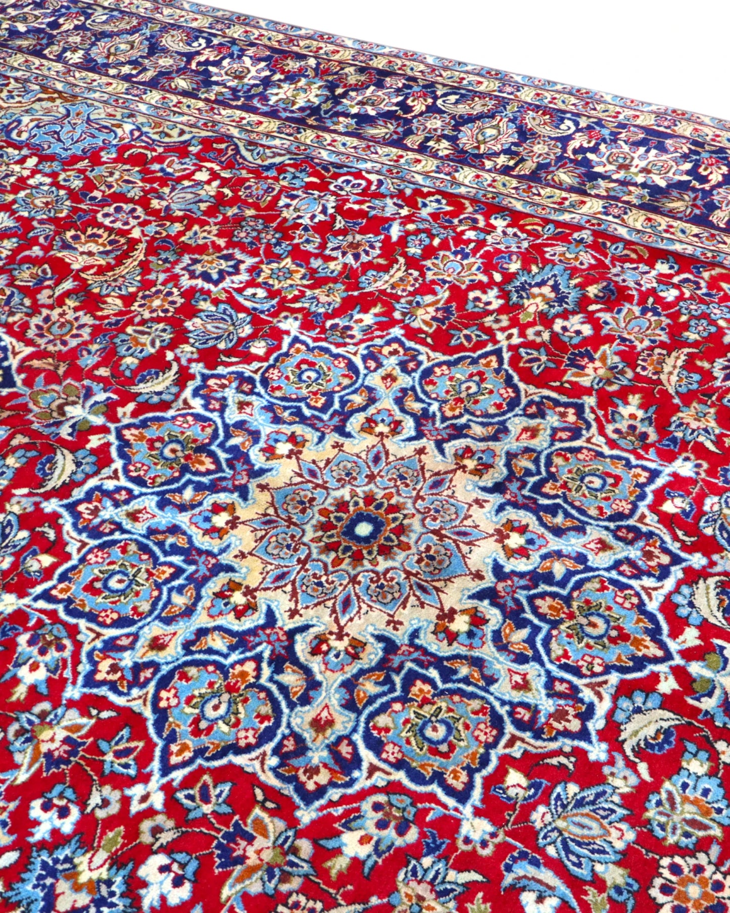 Tappeto persiano Najafabad 500x400 cm, fondo rosso con ampio medaglione centrale blu e cornice floreale scura, annodato a mano in lana vegetale.