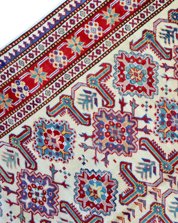 Tappeto Shirvan 165x122 cm con motivi geometrici e floreali in rosso, blu, verde e crema su fondo beige.