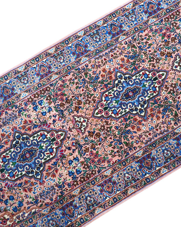 Tappeto persiano Kerman 247x77 cm, corridore con fondo rosa antico e motivi floreali blu e avorio, annodato a mano in lana vegetale.