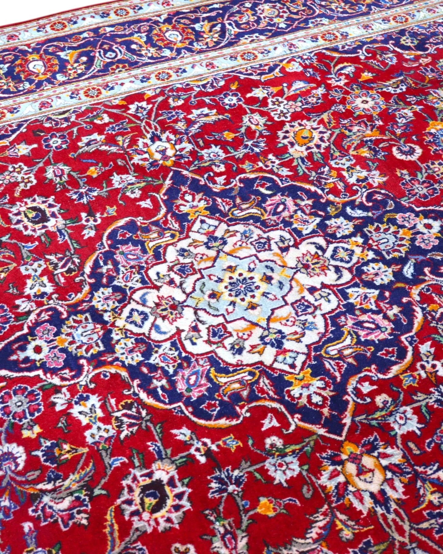 Tappeto persiano Kashan 238x247cm con fondo rosso, medaglione avorio e ricchi motivi floreali blu e oro.
