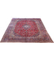 Tappeto persiano Mashhad 385x290 cm, fondo rosso con medaglione centrale e cornice floreale blu e beige, annodato a mano in lana vegetale.