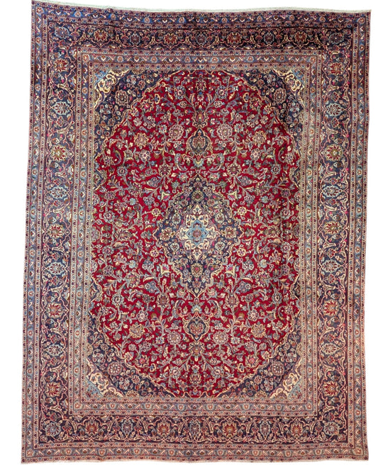 Tappeto persiano Mashhad 385x290 cm, fondo rosso con medaglione centrale e cornice floreale blu e beige, annodato a mano in lana vegetale.