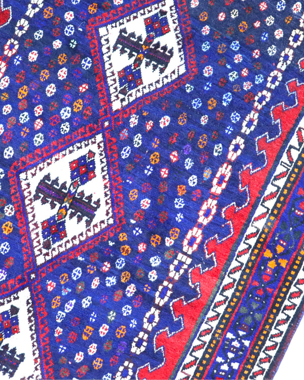 Tappeto Balucestan 215x100 cm annodato a mano, con sequenza di rombi centrali su fondo blu notte e bordi rosso granata.