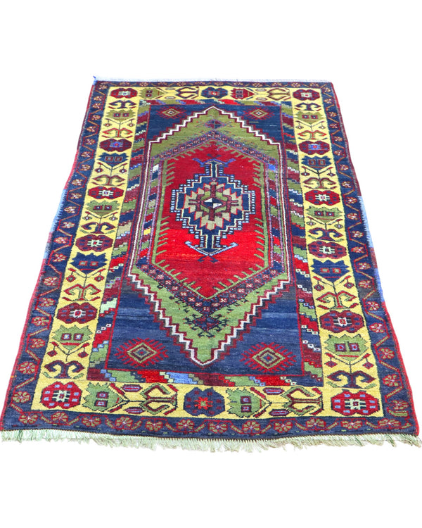 Tappeto Turco 179x103 cm, annodato a mano, con medaglione centrale geometrico rosso, motivi tribali e bordura gialla decorata.