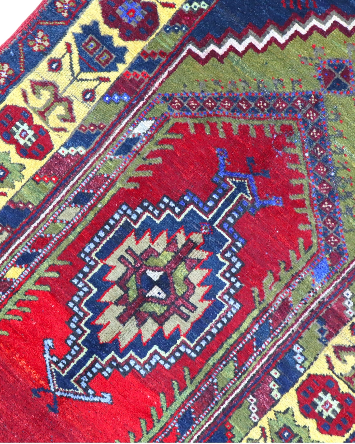 Tappeto Turco 179x103 cm, annodato a mano, con medaglione centrale geometrico rosso, motivi tribali e bordura gialla decorata.