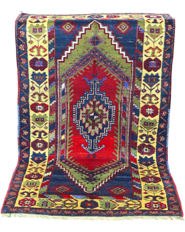 Tappeto Turco 179x103 cm, annodato a mano, con medaglione centrale geometrico rosso, motivi tribali e bordura gialla decorata.