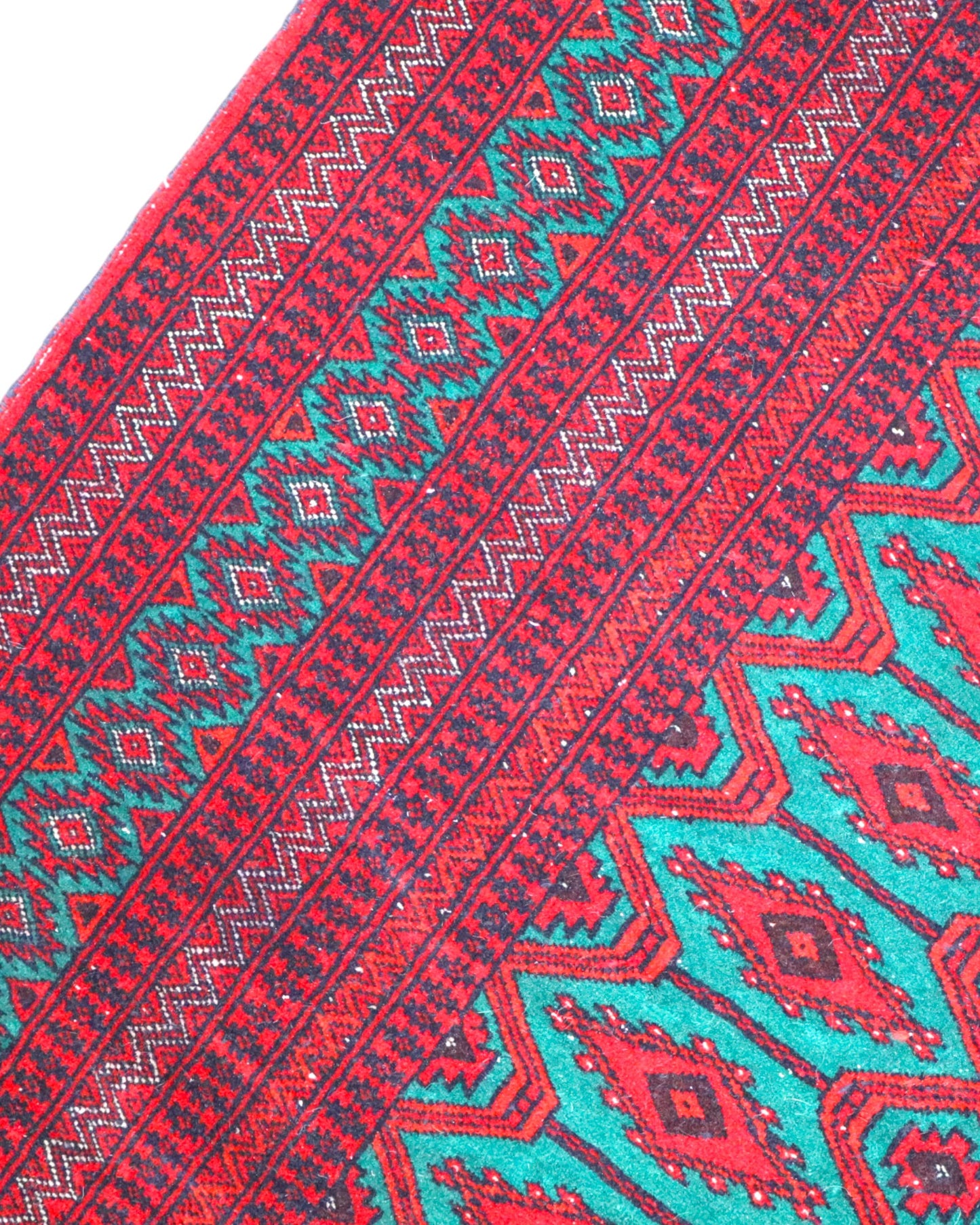 Tappeto Bukhara 172x126 cm annodato a mano, con motivi geometrici gul su fondo verde smeraldo e cornice rossa.