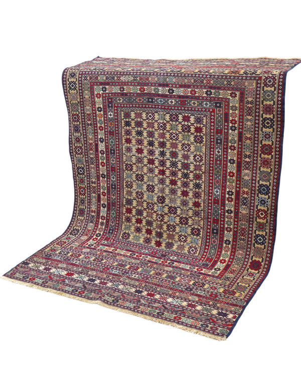 Tappeto Sumakh 180x130 cm con motivi geometrici e floreali in rosso, blu e crema su fondo beige.