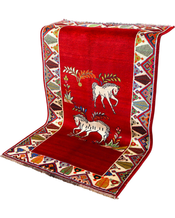 Tappeto Gashgai 185x111 cm annodato a mano, con cavalli stilizzati bianchi su fondo rosso e cornice geometrica multicolore.