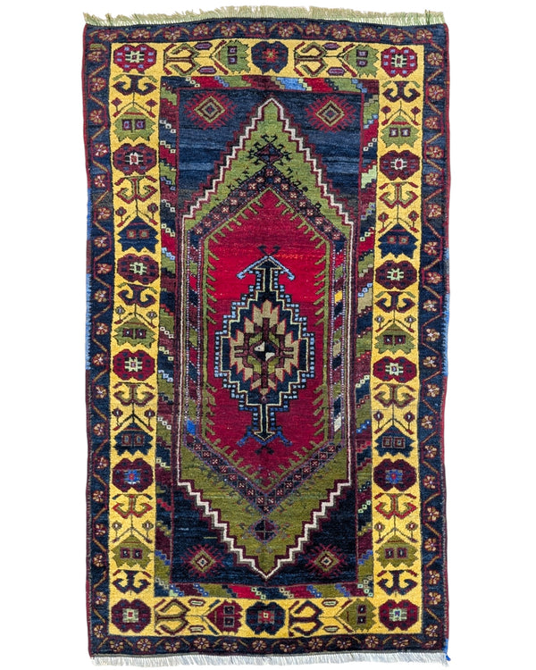 Tappeto Turco 179x103 cm, annodato a mano, con medaglione centrale geometrico rosso, motivi tribali e bordura gialla decorata.