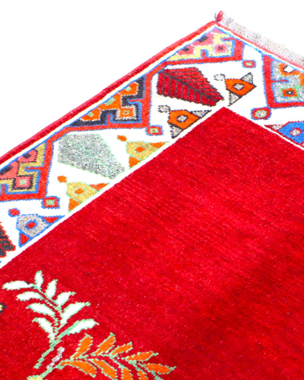 Tappeto Gashgai 185x111 cm annodato a mano, con cavalli stilizzati bianchi su fondo rosso e cornice geometrica multicolore.