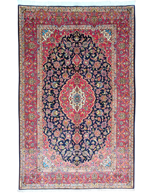 Tappeto Kashan persiano 225x142 cm, annodato a mano, fondo blu notte con motivo floreale e cornice rossa decorata, lana mista seta, certificato di autenticità incluso.