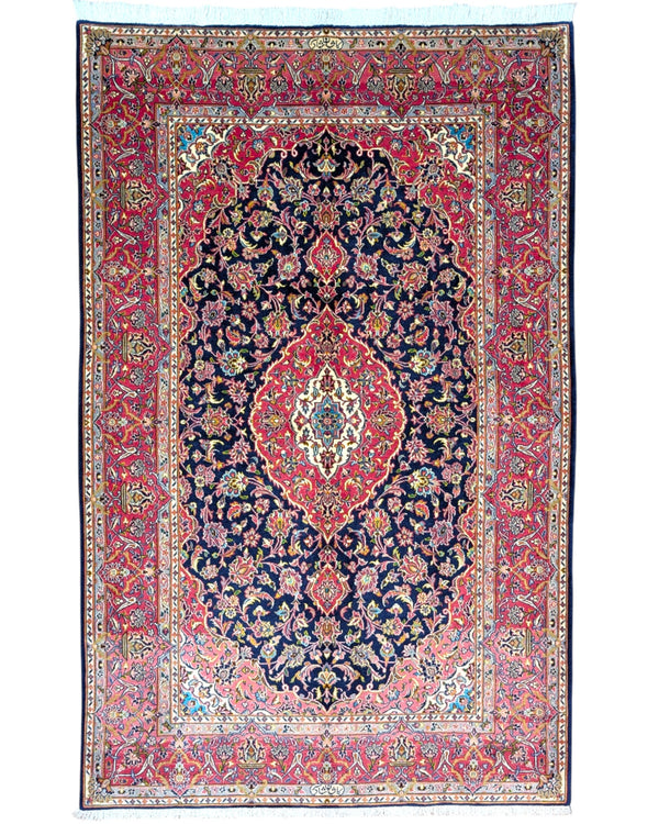 Tappeto Kashan persiano 225x142 cm, annodato a mano, fondo blu notte con motivo floreale e cornice rossa decorata, lana mista seta, certificato di autenticità incluso.