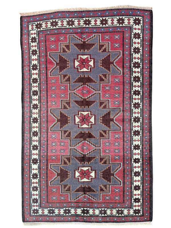 Tappeto Kazak 181x113 cm con motivo geometrico a stelle in rosso, blu e beige, annodato a mano con lana pregiata e ordito in cotone robusto.