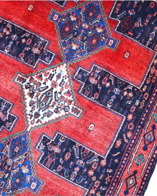 Tappeto Senneh 175x124 cm persiano, annodato a mano, fondo rosso con tre medaglioni geometrici blu e avorio, motivi floreali stilizzati.