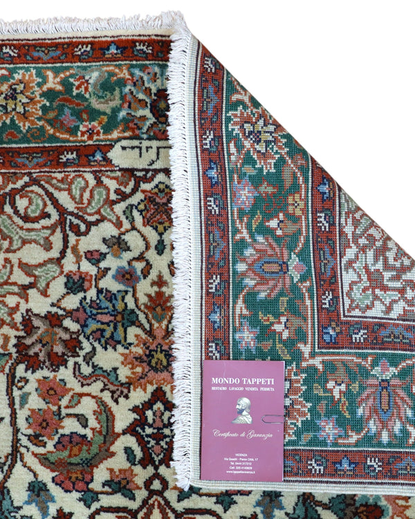 Tappeto Transilvania 180x130 cm annodato a mano, rettangolare, in lana e cotone, fondo avorio con medaglione centrale marrone e motivi floreali in verde, azzurro e rosso.