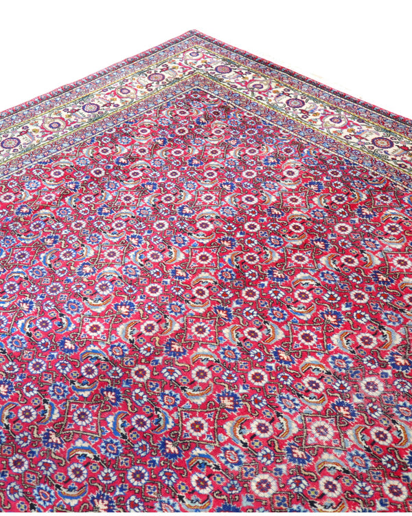 Tappeto Ushak 424x320 cm, fondo rosso con motivi ripetuti geometrici e floreali, cornice giallo-avorio, annodato a mano in lana vegetale, Turchia.