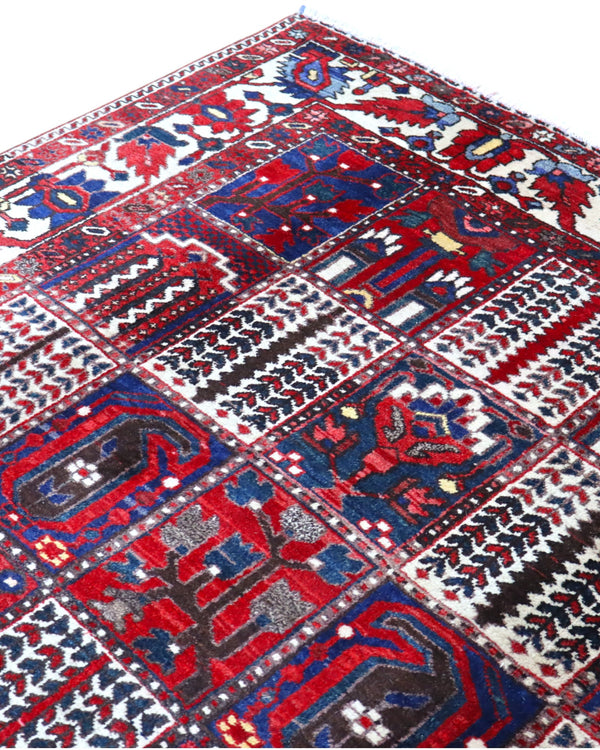 Tappeto persiano Bakhtiar 306x211 cm, motivo a pannelli con decorazioni floreali e geometriche in rosso, blu e avorio, annodato a mano in lana vegetale.