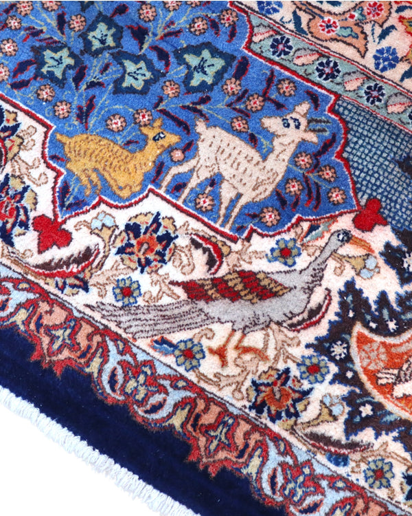 Tappeto persiano Kashmar 384x293 cm, fondo blu con medaglione centrale e motivi floreali e figurativi, annodato a mano in lana vegetale.