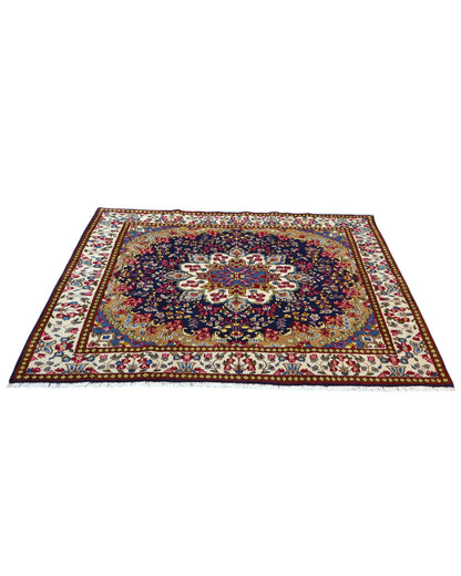 Tappeto Kirman 200x200 cm con motivo floreale centrale in blu, rosso e oro, bordura decorata, annodato a mano con lana pregiata e ordito in cotone.