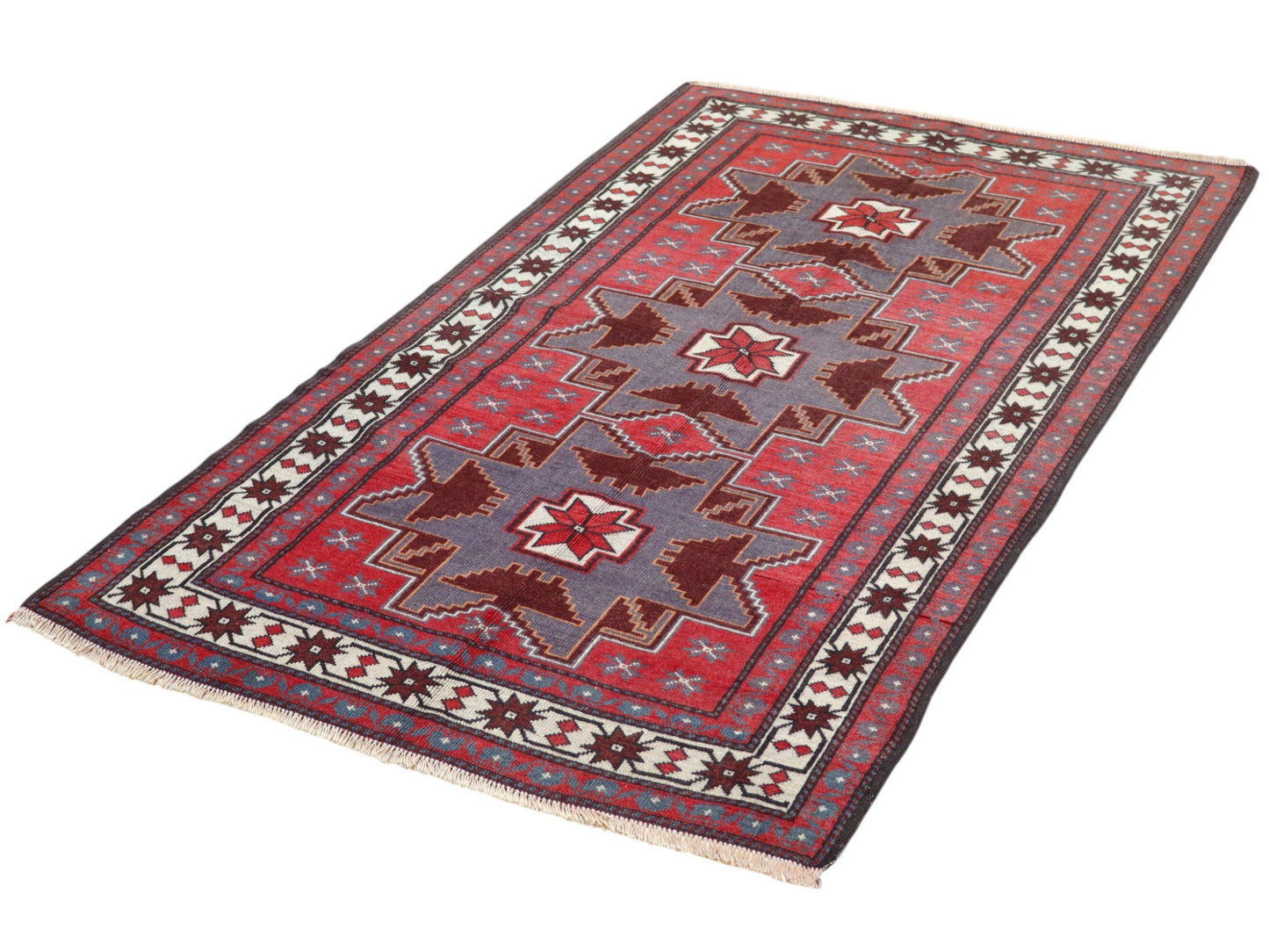 Tappeto Kazak 181x113 cm con motivo geometrico a stelle in rosso, blu e beige, annodato a mano con lana pregiata e ordito in cotone robusto.