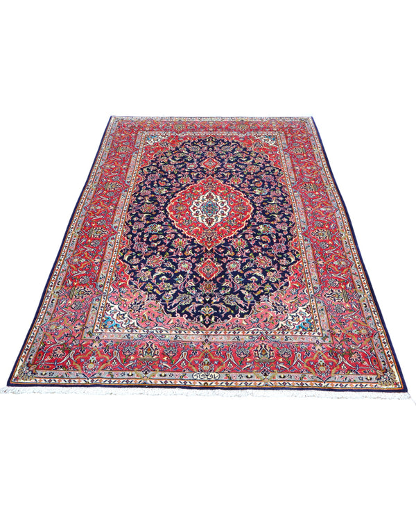 Tappeto Kashan persiano 225x142 cm, annodato a mano, fondo blu notte con motivo floreale e cornice rossa decorata, lana mista seta, certificato di autenticità incluso.