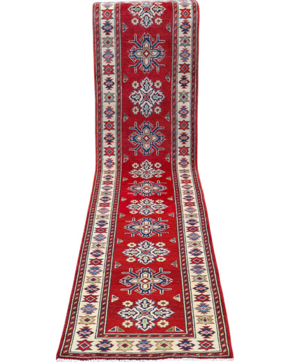 Passatoia Kazak annodata a mano (297x61 cm) in lana, con sfondo rosso melograno e bordo beige, con motivi geometrici afgani.

