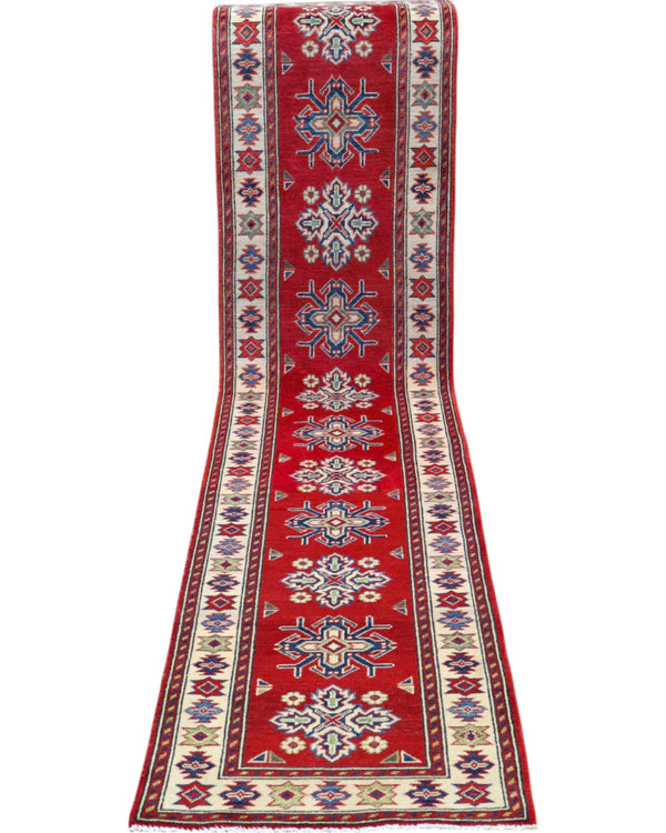 Passatoia Kazak annodata a mano (297x61 cm) in lana, con sfondo rosso melograno e bordo beige, con motivi geometrici afgani.

