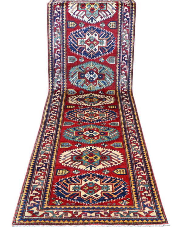 Passatoia Kazak afgana 351x91 cm annodata a mano in lana, con un design audace caratterizzato da motivi geometrici su un fondo rosso intenso.