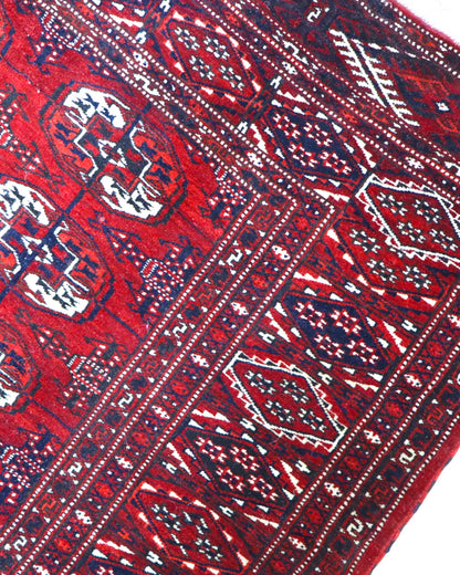 Tappeto Bukhara 324x205 cm con fondo rosso scuro e motivi a gul geometrici in nero, avorio e blu, tramato ed annodato a mano, provenienza Bukhara.