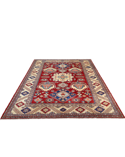 Tappeto Kazak 330x224 cm con fondo rosso, medaglione centrale avorio e motivi geometrici blu e azzurri, tramato ed annodato a mano, provenienza Caucaso.