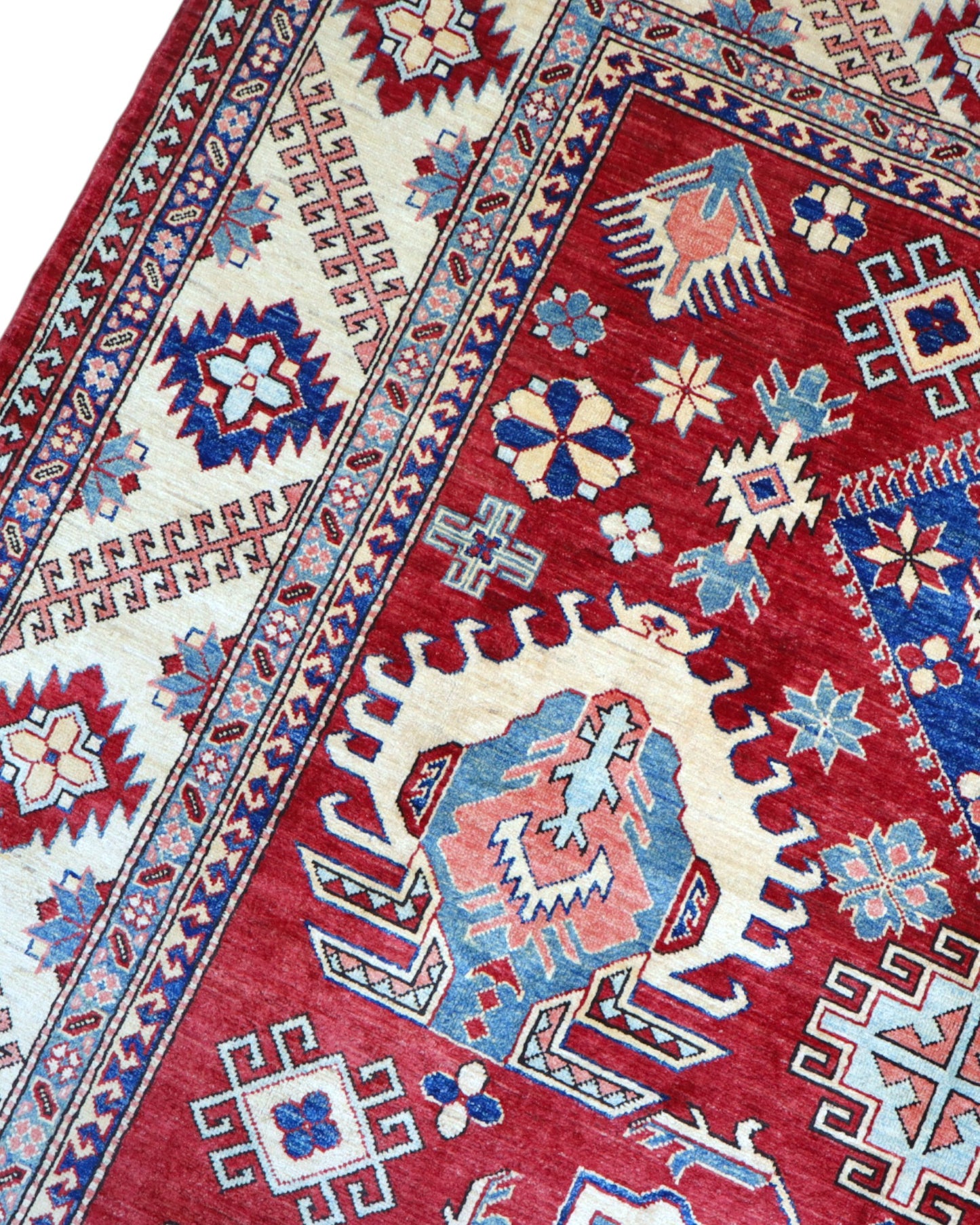 Tappeto Kazak 330x224 cm con fondo rosso, medaglione centrale avorio e motivi geometrici blu e azzurri, tramato ed annodato a mano, provenienza Caucaso.