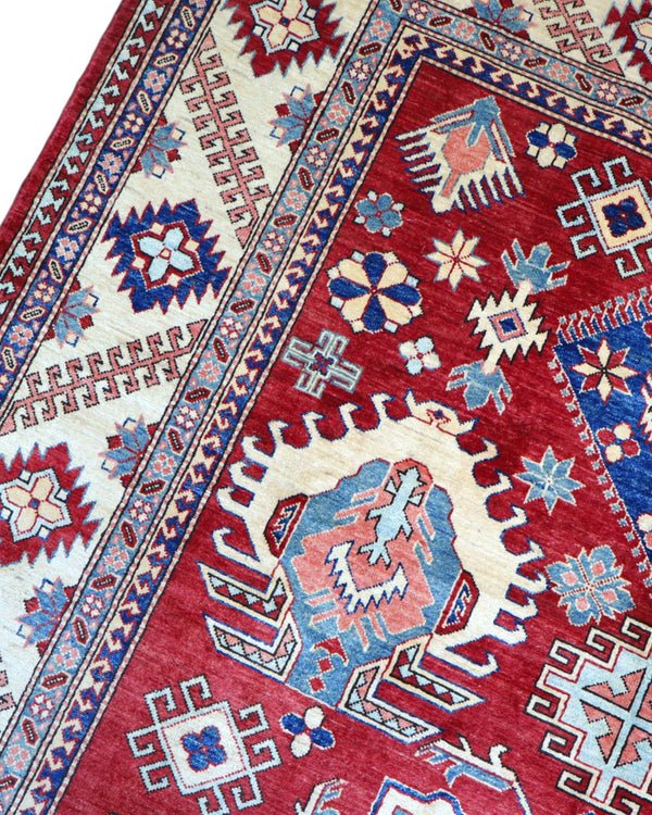 Tappeto Kazak 330x224 cm con fondo rosso, medaglione centrale avorio e motivi geometrici blu e azzurri, tramato ed annodato a mano, provenienza Caucaso.