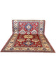 Tappeto Kazak 330x224 cm con fondo rosso, medaglione centrale avorio e motivi geometrici blu e azzurri, tramato ed annodato a mano, provenienza Caucaso.