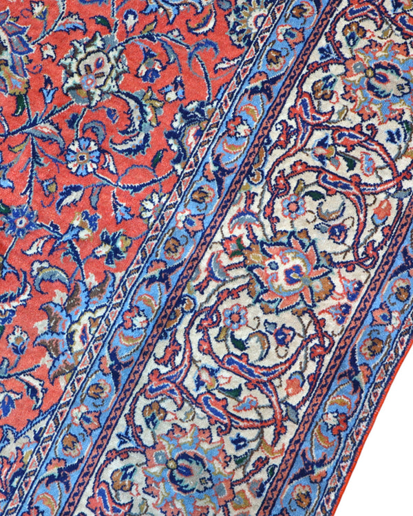 Tappeto persiano Saurk 345x240 cm, fondo rosso corallo con medaglione blu e cornice floreale chiara, annodato a mano in lana vegetale.