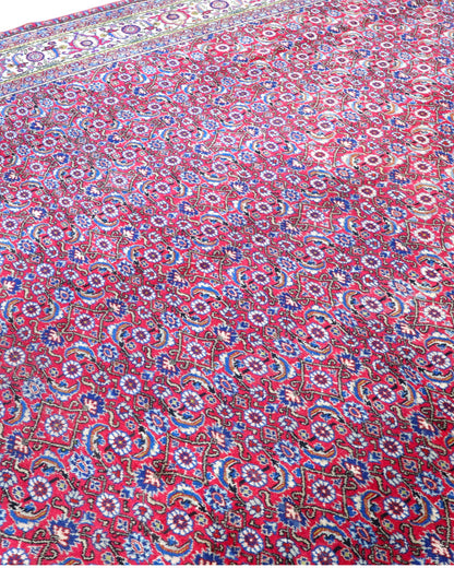 Tappeto Ushak 424x320 cm, fondo rosso con motivi ripetuti geometrici e floreali, cornice giallo-avorio, annodato a mano in lana vegetale, Turchia.