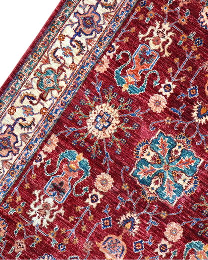 Tappeto Farahan 176x127 cm con motivi floreali e geometrici in rosso, blu, verde e oro su fondo beige.