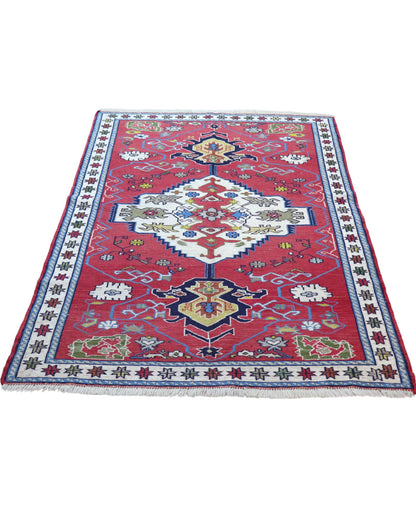 Tappeto Kilim 190x122 cm con motivi geometrici in rosso, blu, giallo e verde su fondo beige.