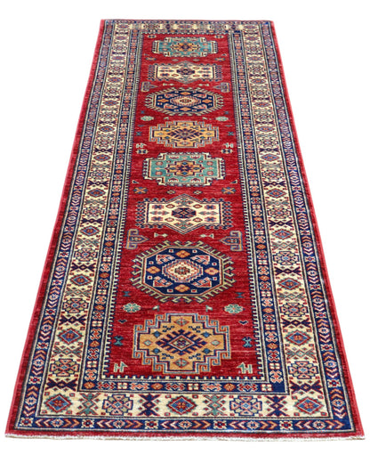 Tappeto Kazak 236x82 cm, corridore afghano annodato a mano in lana, fondo rosso con motivi geometrici blu e verdi.