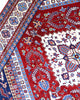 Tappeto Shirvan 274x184 cm con fondo rosso, medaglione centrale blu e avorio e bordure geometriche multicolori, tramato ed annodato a mano.
